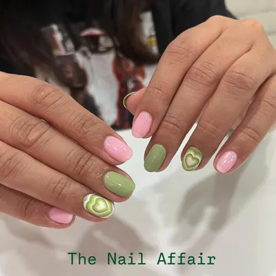 A cute and trendy design combining pastel pink and sage green nails. The accent nails feature a fun, hand-painted heart swirl pattern for a playful touch.