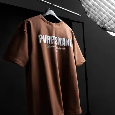 A behind-the-scenes look at a t-shirt shoot. We use professional lighting and a dark background to make the 3D puff-print logo on this brown t-shirt stand out.