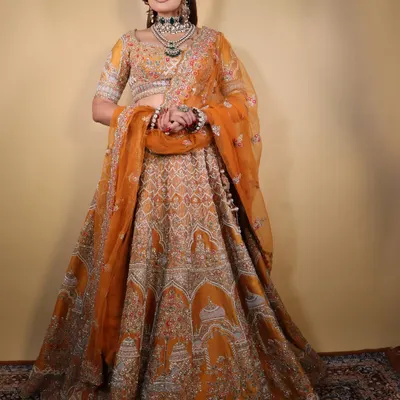The "Marigold Muse" in her full glory. This image showcases the complete look with the stunning orange lehenga, a perfect inspiration for a vibrant wedding event.