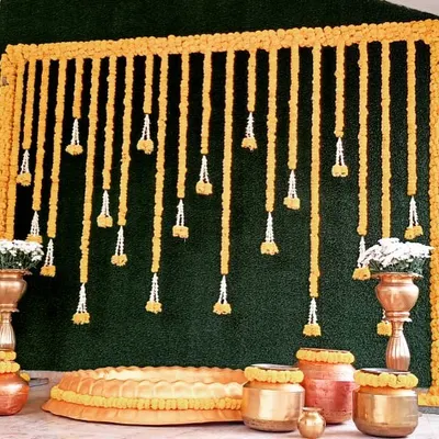 A classic Haldi ceremony setup we did, featuring a backdrop of marigold garlands and a collection of traditional brass and copper pots (urulis).