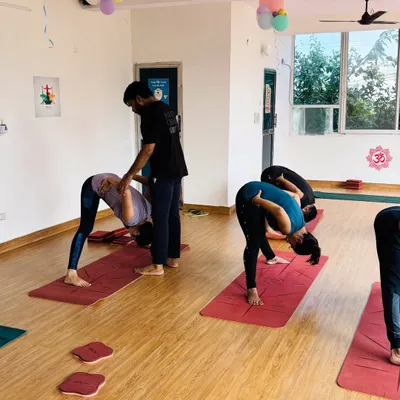 Providing a gentle adjustment in a forward fold. This helps the student release tension in the lower back and deepen the stretch in the hamstrings safely.