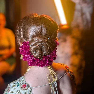 A close-up of a stunning floral bun. I used deep magenta flowers to match the bride's lehenga, weaving them into a classic updo and adding delicate pearls for a touch of elegance. This style is both secure and beautiful.