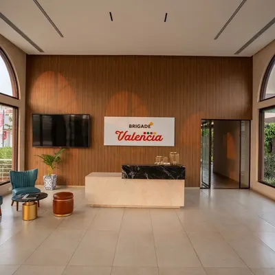 The reception area of the Brigade Valencia office features a double height space with large arched windows. The warm wood paneling and minimalist furniture create a welcoming first impression for visitors.