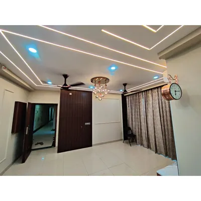 A close-up of a false ceiling design with multiple layers of cove lighting and a modern chandelier. This kind of lighting design adds depth, ambiance, and a sense of luxury to any room.