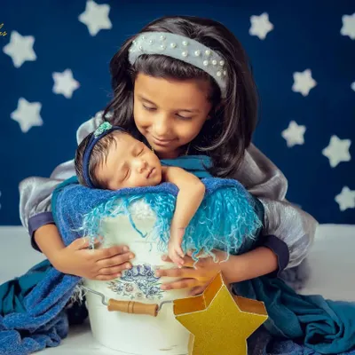 A proud big sister holds her new baby sibling. I guide older children to interact gently and lovingly, resulting in authentic portraits that showcase their special new bond.