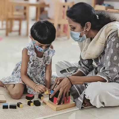 A guide sits with a child as she works with the Trinomial Cube. My role is to observe and offer support when needed, allowing the child to lead the discovery while ensuring she feels encouraged and understood.