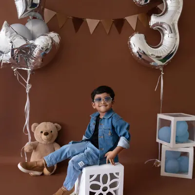 This cool three-year-old is ready to celebrate his birthday in style, rocking a denim jacket and sunglasses.