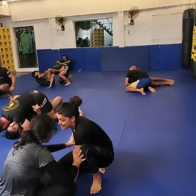 A wide shot of a busy no-gi class. Members are paired up, drilling techniques and getting in live rolls.