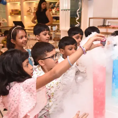 Children gather around, captivated by a hands-on science show with colorful, smoking beakers. This safe and exciting science activity is a huge hit at birthday parties, making learning fun.
