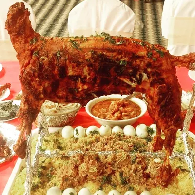 For a truly unforgettable feast, we offer a whole roasted lamb. This dish serves as a magnificent centerpiece for a groom's dinner table or any milestone celebration, served on a bed of aromatic rice and garnished for presentation.