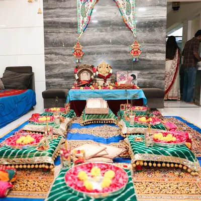 A closer view of the Lagan Lakhwanu setup, focusing on the ritual area. You can see the decorated bajots for seating, each with a plate of flowers, and the main table for the puja, all set against a traditional backdrop.