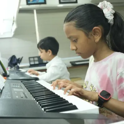 A young student practices finger placements on the keyboard, reading sheet music. Our classes focus on building strong fundamentals in both practical skills and music theory.