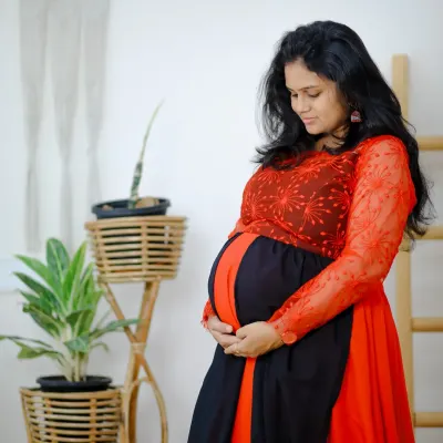 A gentle moment captured during a maternity shoot. Our red and black rental gown is designed to comfortably and beautifully highlight your baby bump.