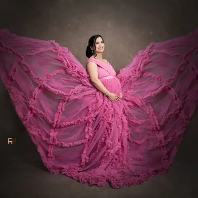 The butterfly effect. This dramatic pose with a flowing pink gown creates a stunning butterfly shape, symbolizing transformation and new beginnings. We love getting creative to produce unique, artistic maternity portraits.
