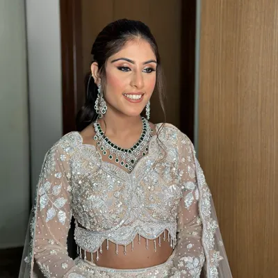 A sangeet bridal vision in an ivory and shimmer lehenga. This look features soft pink eyeshadow, a flawless base, and a natural lip color.