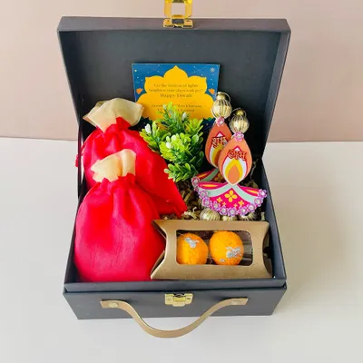 This compact grey suitcase hamper is perfect for Diwali. It holds festive goodies like decorative diyas, chocolates, and small pouches of treats, complete with a personalized festive card.