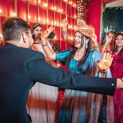 The energy of a baaraat is unmatched. This candid shot captures the bride dancing with abandon as she joins the groom's procession, surrounded by the joyful celebration of friends and family.