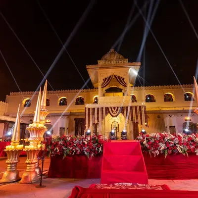 A grand stage setup for a Sangeet at Jagmandir, featuring regal decor, bold red florals, and dramatic spotlights to create a powerful focal point for the evening's performances.