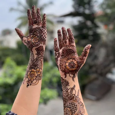 A lovely floral mehendi design, captured in beautiful natural light. The outdoor setting really makes the details of the flowers and checkerboard patterns pop.