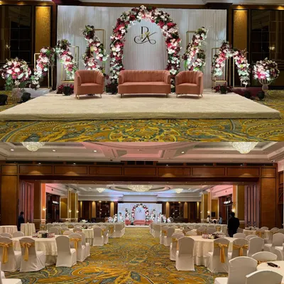 A classic and elegant reception stage with a blush and maroon floral arch. The bottom frame shows the complete ballroom setup, highlighting how we design the stage to be the stunning centerpiece of the entire space.