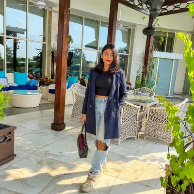 A great blazer is a cornerstone of power dressing. Here, I've styled a longline navy blue blazer with a simple black crop top and ripped jeans for a look that's sharp yet edgy.