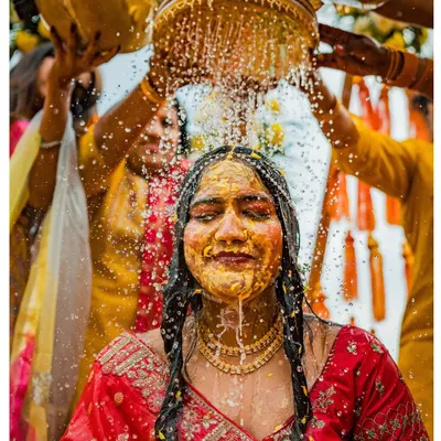 A bride is showered with water and turmeric during her Haldi ceremony, a moment of pure, unadulterated joy and tradition.