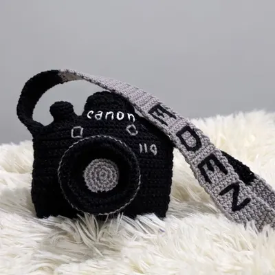 A unique, custom-made crochet camera pouch. This one was personalized with the brand 'Canon' and the name 'Eden' on the strap.