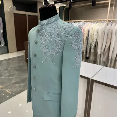 A stunning pastel mint green Jodhpuri suit displayed on a mannequin. The delicate, tonal threadwork and bead embroidery on the shoulder and collar make this a sophisticated choice for a day event.