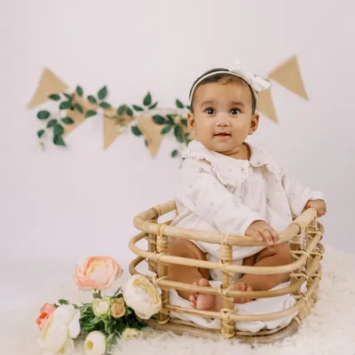 A perfect six-month "sitter session" portrait. This little girl, sitting up on her own in a sweet basket, is celebrating being halfway to one.