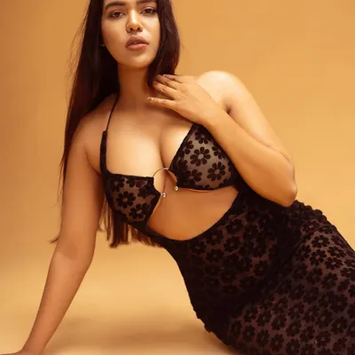 A bold and confident pose for a fashion portfolio. The lighting is set to highlight the model's features and the unique texture of the sheer floral dress against a warm, neutral backdrop.