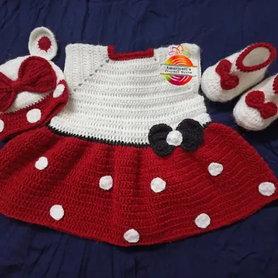 A complete Minnie Mouse-themed baby set. This includes a red and white polka dot dress, matching booties with a little bow, and a cap with Minnie ears. It’s a perfect gift for a special little girl.