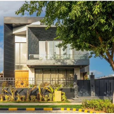 An angled view of our award-winning zinc-clad residence, highlighting the interplay between the textured shingle facade and the smooth, monolithic volumes. The large window openings are strategically placed to capture natural light while maintaining privacy for the residents.