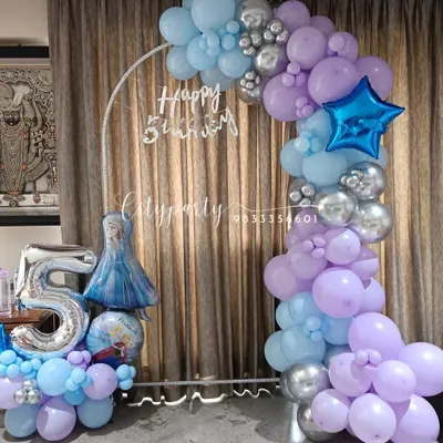 A 'Frozen' themed balloon arch for a 5th birthday, designed with pastel blue, purple, and chrome silver balloons. The setup includes a large '5' foil balloon and an Elsa character balloon.