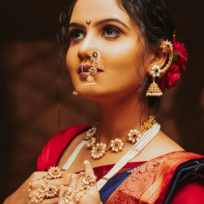 A classic Maharashtrian bridal look. The warm, dramatic lighting highlights the intricate details of the jewellery, the nath, and the beautiful expression.