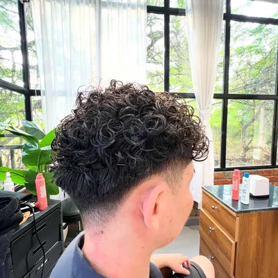 This men's perm adds incredible texture and volume. Paired with a low taper fade, it's a modern and stylish look.