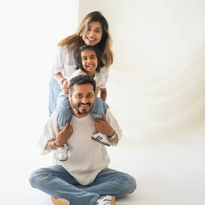 The classic family totem pole! A daughter on her dad's shoulders with mom peeking from behind. This is such a fun and happy pose for a studio family portrait.