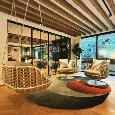 This informal seating area is designed for relaxation. It features a hanging wicker swing chair and matching swivel chairs, creating a peaceful corner to unwind and break away from a formal setting.