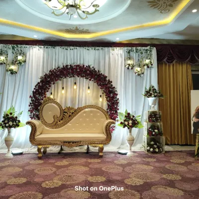 This elegant baby shower stage in Chandapura features a circular arch of deep red and white flowers, classic seating, and balanced lighting. It’s a complete setup designed to be the perfect backdrop for photos of the happy couple.