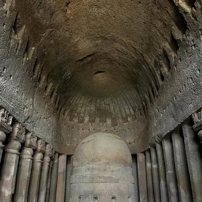 The main prayer hall at Kanheri Caves, showing the massive stone stupa under a chaitya arch, a marvel of ancient rock-cut architecture.