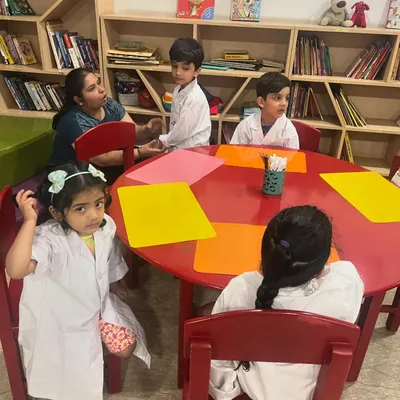Our Science Camp is in full swing. Here, a group of young scientists in their lab coats are gathered around the table, ready for their next lesson.