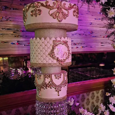 A spectacular chandelier wedding cake. This grand design features ornate gold molding, crystal-effect bands, and a custom monogram, all supported by a glittering chandelier stand.