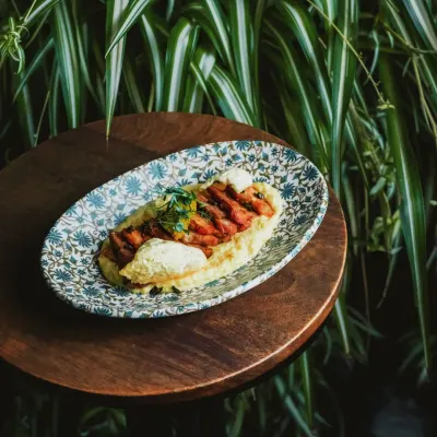 This smoked pork belly, served on a beautiful patterned plate, perfectly encapsulates the combined brilliance of our chefs: the warmth of comfort and the depth of story.