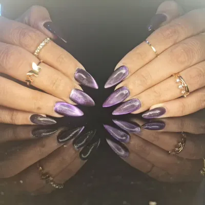 A stunning set of purple cat-eye nails on long stiletto extensions, showing a beautiful diagonal shimmer that moves with the light.