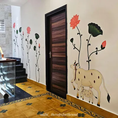 This wide shot shows how the Pichwai mural, with its cow-calf motif and climbing lotuses, elegantly frames the doorway and complements the traditional Indian flooring.