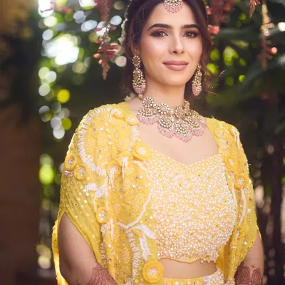 A perfect blend of tradition and glow for a Haldi ceremony. The bride's makeup features soft pink tones that beautifully complement her yellow outfit.