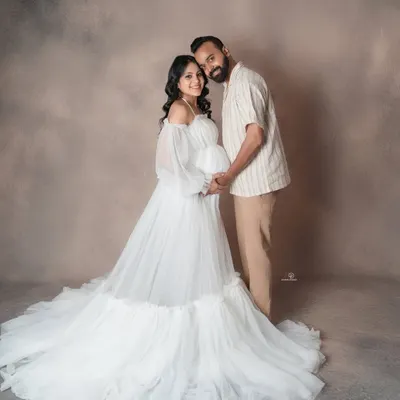 An ethereal and dreamy maternity portrait. The flowing white gown and soft lighting create a truly angelic look for the mom-to-be in this studio session.