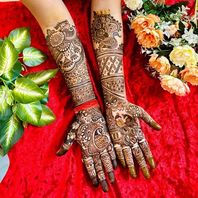 A complete view of a grand bridal mehndi design. This full-coverage look features peacocks, paisleys, and floral patterns, extending from the fingertips to the elbows for a stunning effect.