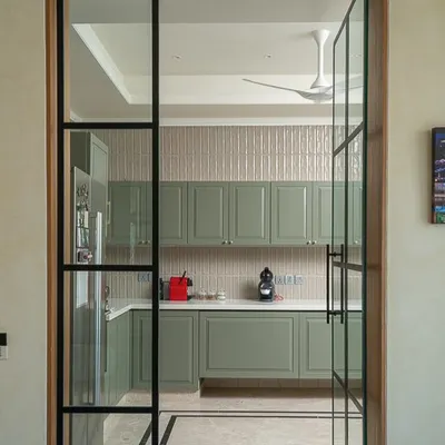 This kitchen is a haven of earthy elegance. I used calming sage green cabinetry, framed by glass and black metal doors, to create a space that is grounded, open, and connected to the rest of the home.