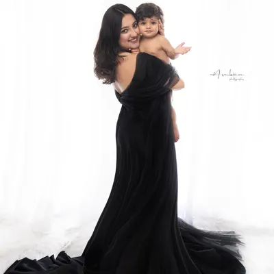 A classic mother and child portrait. The flowing black gown and the simple, high-key background create a look of pure elegance and focus all attention on their connection.