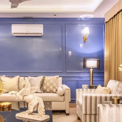 A complete living room setting we designed, featuring a neutral-toned sofa and striped accent chairs against a rich periwinkle blue wall with classic moulding. The space is anchored by a dark, contemporary coffee table, creating a balanced and inviting atmosphere.